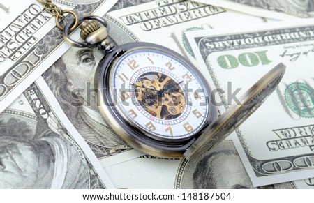 Concept of time is money, old watch on a pile dollar notes