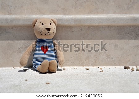 A lonely plush bear sitting on stairs