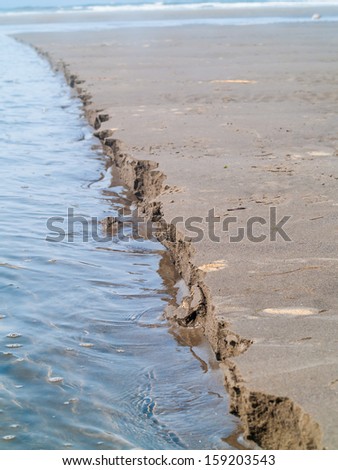 A Line of Wet Sand Eroding at the Beach at the Water\'s Edge