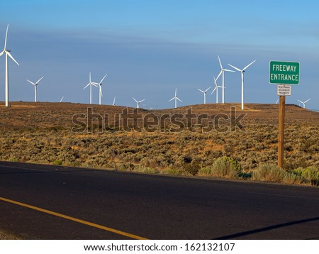 A Windmill Farm on a Mountain Beside an Interstate Freeway at Dusk