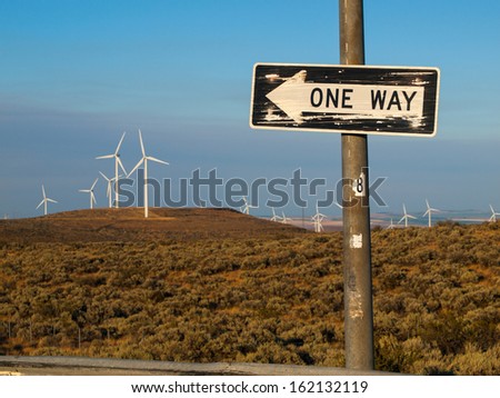 A Windmill Farm on a Mountain with One Way Signs Pointing to a Freeway at Dusk