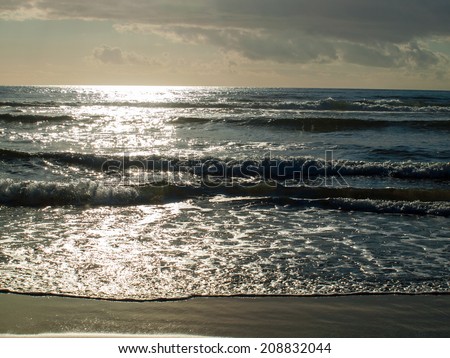 Blue Ocean Waves Breaking on the Beach as the Sun is Going Down