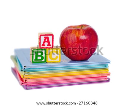 ABC Blocks and a Red Apple arranged on a stack of rainbow colored children\'s books.  Isolated on white.