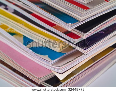 An uneven stack of magazines filling the frame from top to bottom focus on corner edge