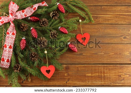 Christmas Wreath - red cones and red wooden hearts on green spruce branches on wooden background