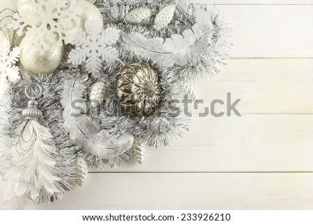 Christmas decoration - silver balls, silver cones, white snowflakes, silver pendants with feather, silver feathers, silver garland on white wooden background