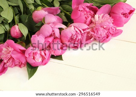 Bouquet of small pink peonies on white painted wooden background