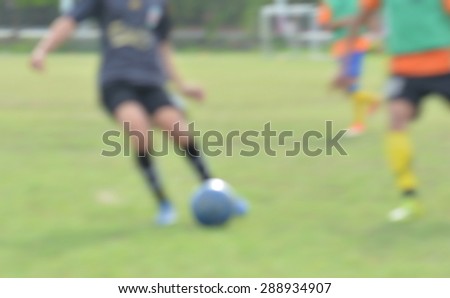 blur young children playing soccer on green soccer pitch