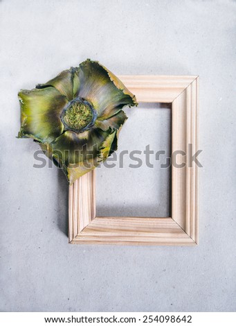 Minimalism empty wooden frame with decoration in a shape of flower on grey paper background