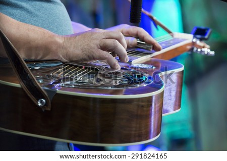 Classic Dobro guitar played my a master on concert. Focused on hand.