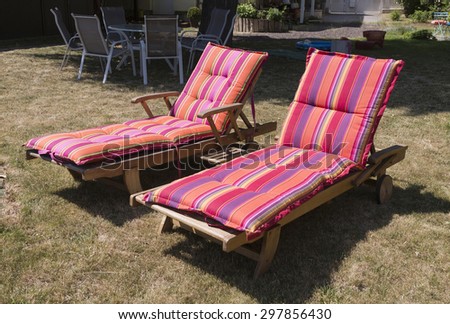 Two lawn chairs on the sun-drenched garden with colorful covers..