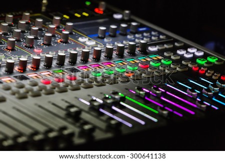 Audio mixer mixing board fader and knobs with selective focus on central buttons, Music mixing console with backlit buttons