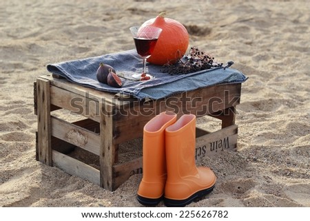 Autumn scenery with pumpkin and rain boots in the box after the wine on the beach/ 	Autumn scenery on the wine box on the beach