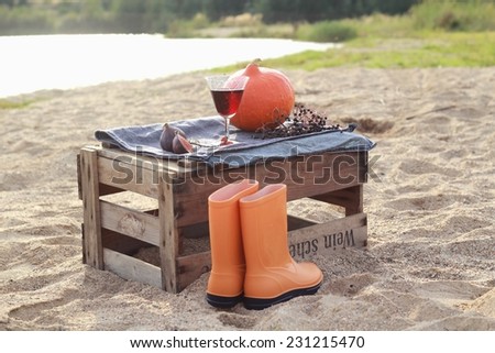 Autumn scenery with pumpkin and rain boots in the box after the wine on the beach/Autumn picnic on the beach