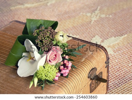 Small bouquet of pink and white flowers on vintage suitcase; vintage filter