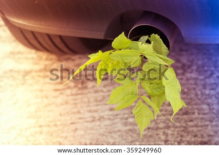 Car pipe exhaust muffler rejecting carbon dioxide with a plant with green leaves growing outside, slide leak vintage style