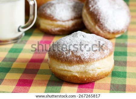 Morning breakfast with donuts and milk on checkered tablecloth.