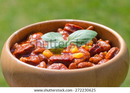 A woody bowl of homemade chili bean goulash with sausage and corn, selective focus, hard light