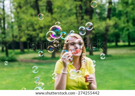 Young beautiful girl blowing bubbles summer outdoors.  Selective focus on bubbles. Blurred face.
