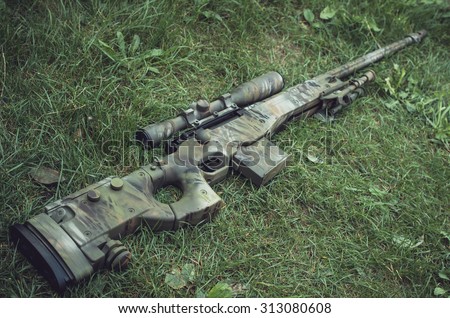 Camouflaged sniper rifle with spotting scope and equipment. Photo edited into warfare look and dark atmosphere. Selective focus.