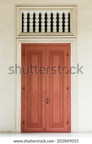 Ancient red door with white door frame and air passage.