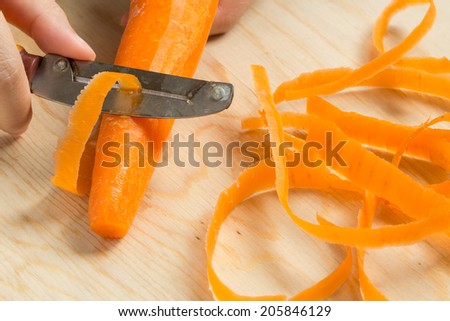 Someone is peeling the carrot for cook.