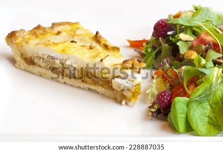 Tart with goat cheese and salad with raspberry, lettuce and tomatoes
