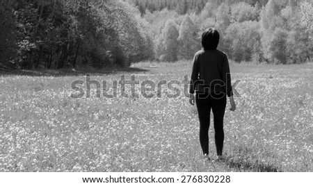 Middle aged lady overlooking meadow by the forest
