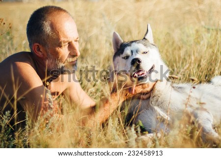 Old man plays with his dog Siberian Husky. Lifestyle. Active recreation. Photo toned style Instagram filters.