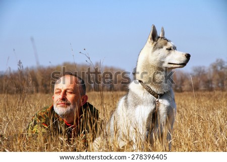 The old man playing with his dog. Man and dog in the hunt. Siberian husky.