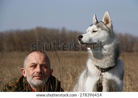 The old man playing with his dog. Man and dog in the hunt. Siberian husky.