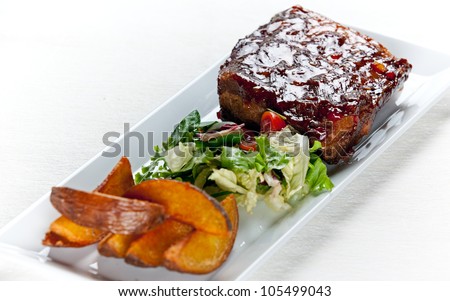 Juicy honey glazed pork ribs with side salad and baked potatoes.