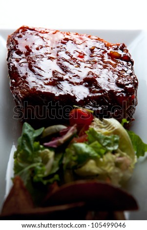 Juicy honey glazed pork ribs with side salad and baked potatoes.