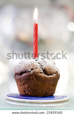 A tasty chocolate muffin with candle isolated on color background. Candle at focus and shallow depth of field