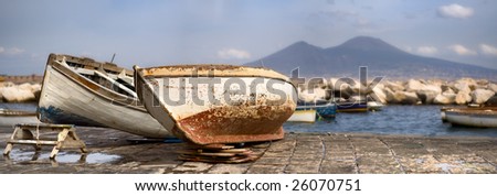 Two old boats on a bank by the sea with a big volcano mountain in the background
