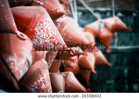 Red  sea buoys hang on a wall. Shallow depth of field and focus on the foreground buoy