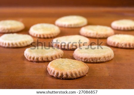 Some round cookies arranged to form a triangle shape on a wooden background