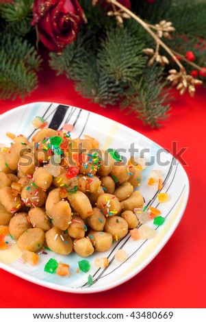 A square colorful plate of Struffoli on a red background: a typical christmas sweet of Naples, Italy.