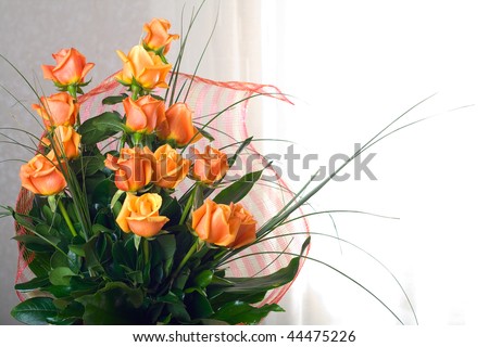 A vase of beautiful orange roses with green decorations on a white background
