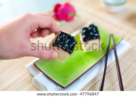 Japanese cheesecake treats served on an asian plate with chop sticks. Shallow depth of field on cheesecake treat and hand.