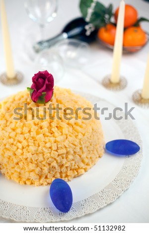 Mimosa cake made of sponge cake, cream patisserie, whipped cream and orange flavored. Decorated with small cubes of spongecake all over. Shallow depth of field on rose and cake front