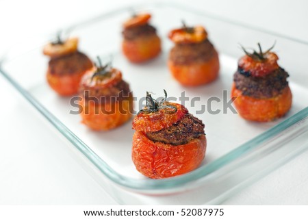 Baked stuffed tomatoes with veal minced meat, eggs, cheese, basil, black pepper, onion, garlic, mortadella. Shallow depth of field on one tomato