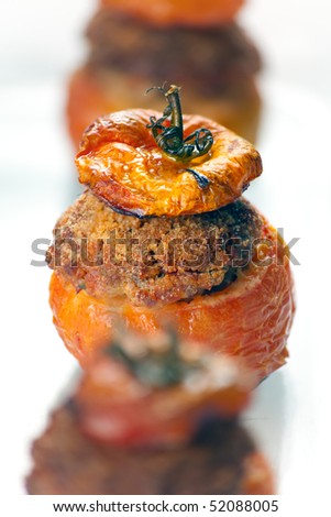 Baked stuffed tomatoes with veal minced meat, eggs, cheese, basil, black pepper, onion, garlic, mortadella. Macro shot: shallow depth of field on tomato\'s top and stuffing