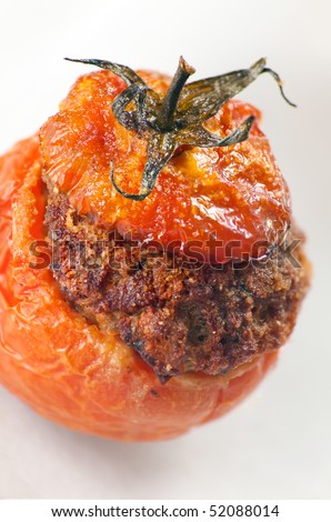 Baked stuffed tomatoes with veal minced meat, eggs, cheese, basil, black pepper, onion, garlic, mortadella. Macro shot: shallow depth of field on tomato\'s top and stuffing