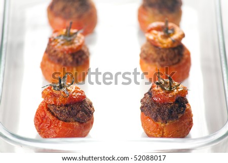 Baked stuffed tomatoes with veal minced meat, eggs, cheese, basil, black pepper, onion, garlic, mortadella. Shallow depth of field on first two tomatoes