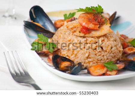A plate of fancy italian risotto alla pescatora with seafood and fresh parsley