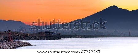the port of naples in the twilight at dawn, warm sunrise colors in the sky and light blue sea.