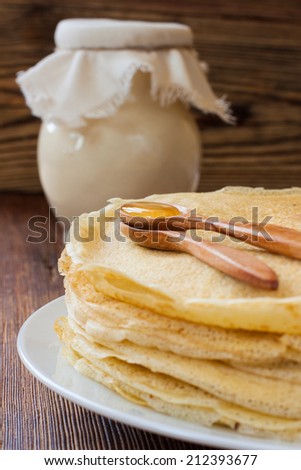 Russian pancakes with wooden spoons, honey and clay jug