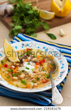 Russian dishes - cabbage soup with white beans, lemon and sour cream.