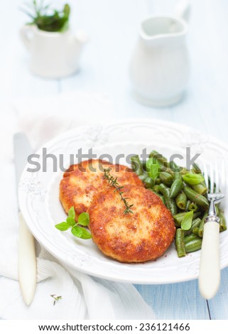 turkey cutlets with a side dish of green beans on a white plate